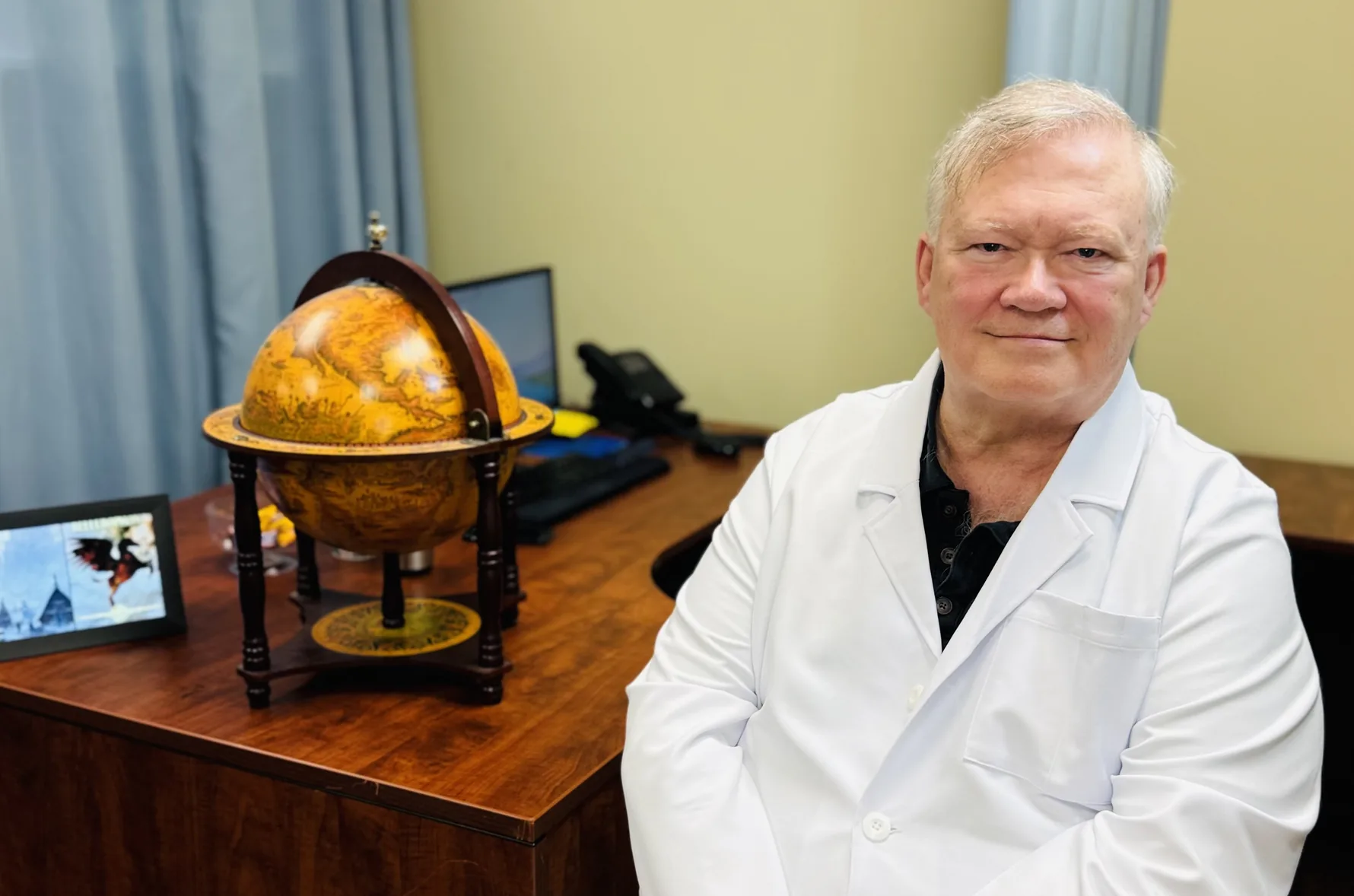 Dr. Cole in a white lab coat seated at his office desk