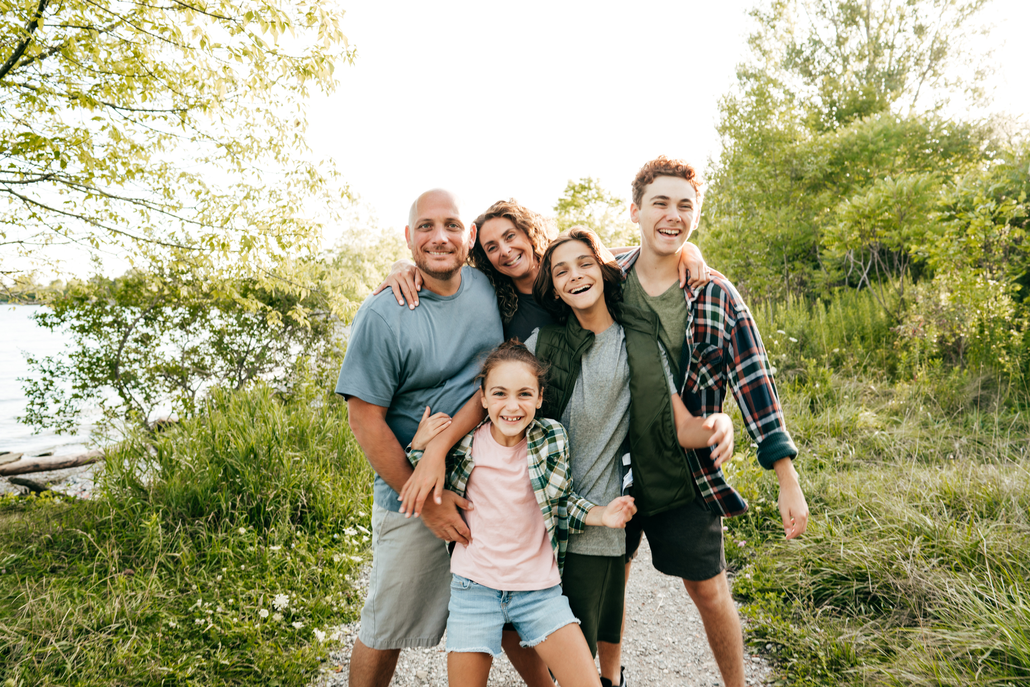 Family bonding and having a fun time together at the lake. Three kids and parents embracing and smiling at the camera. three kids and parents embracing and smiling at the camera next to a lake